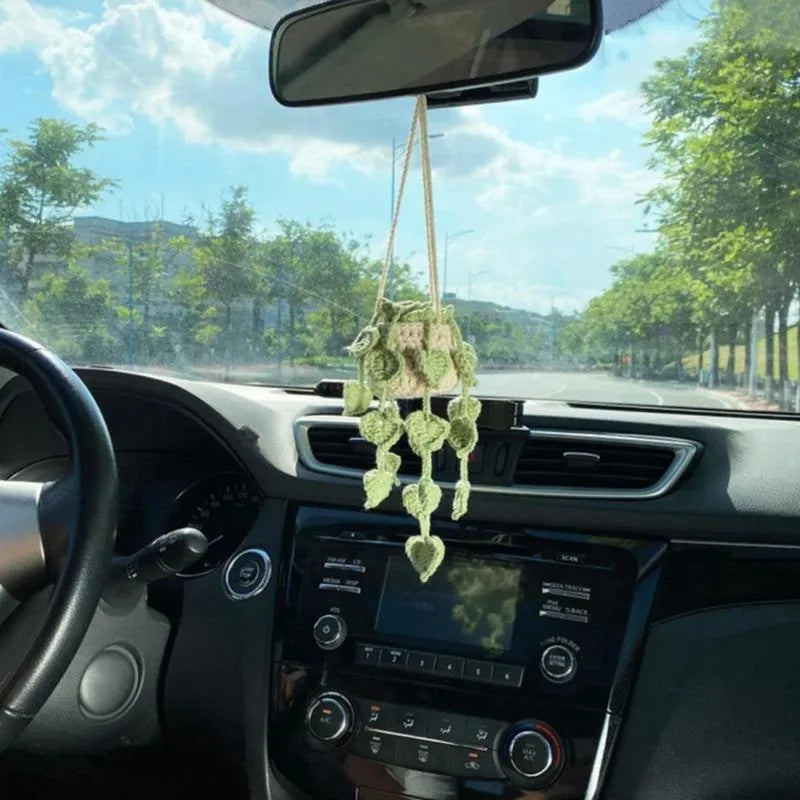 Green and white crocheted wool car plant decoration with a white hanging rope.