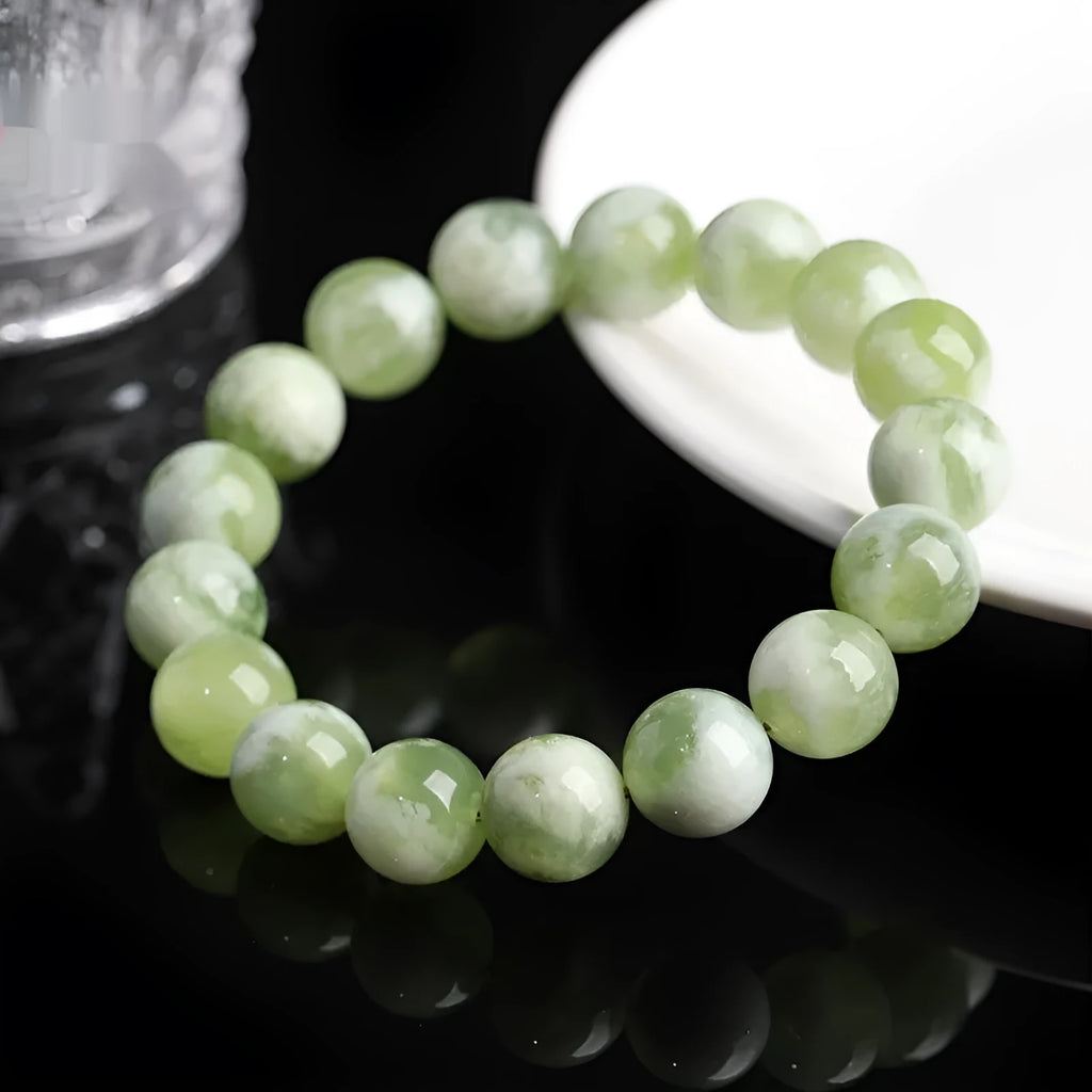 Green milk-in-water Xiuyan jade bracelet with polished geometric beads on a wrist.