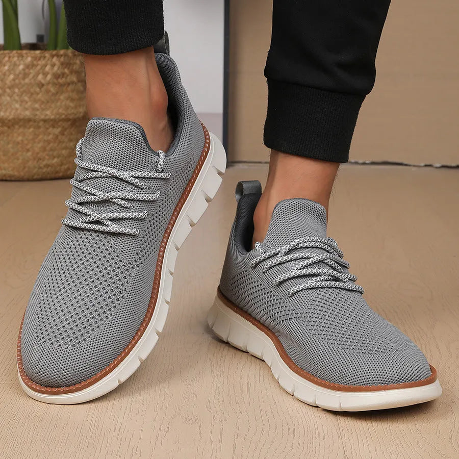 Men's grey and black mesh fabric casual sneakers with a round toe and low heel on a plain background.