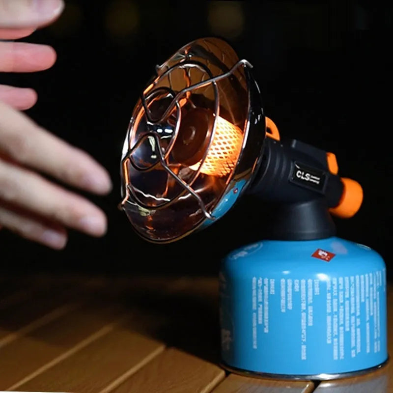 Black and orange portable outdoor heating stove with automatic ignition on a campsite.