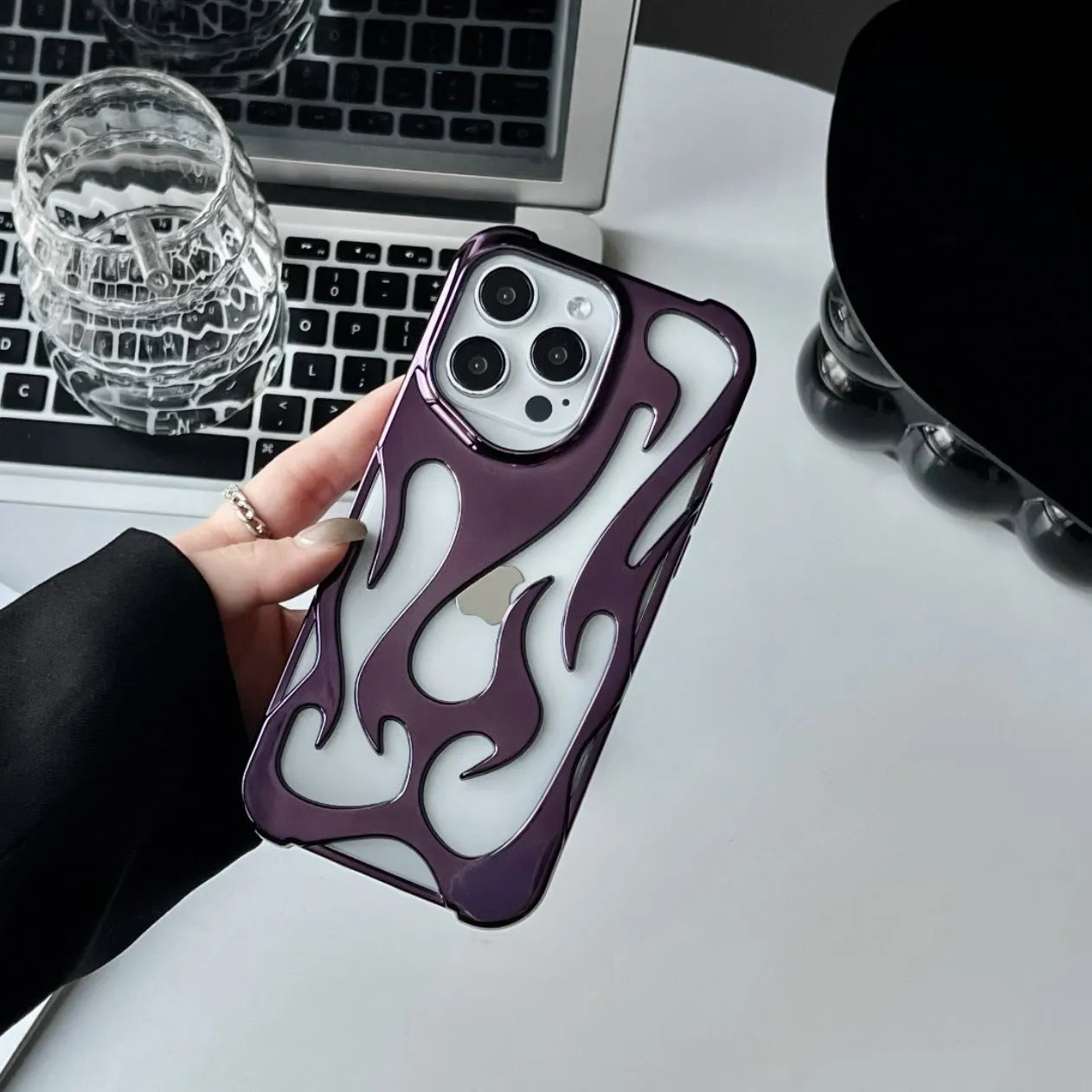 Electroplated hollow flame pattern phone case for iPhone on a table, showing silver metallic finish and cut-out design.