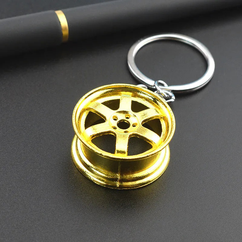 Zinc alloy car wheel hub keychain in gold, silver, and black colour options.