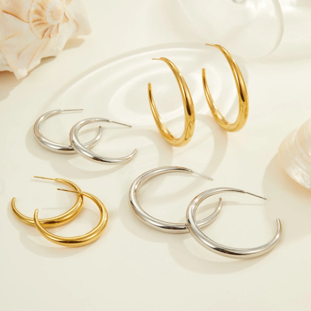 A pair of round titanium steel hoop earrings with an 18K gold plated finish, shown in large and small size options.