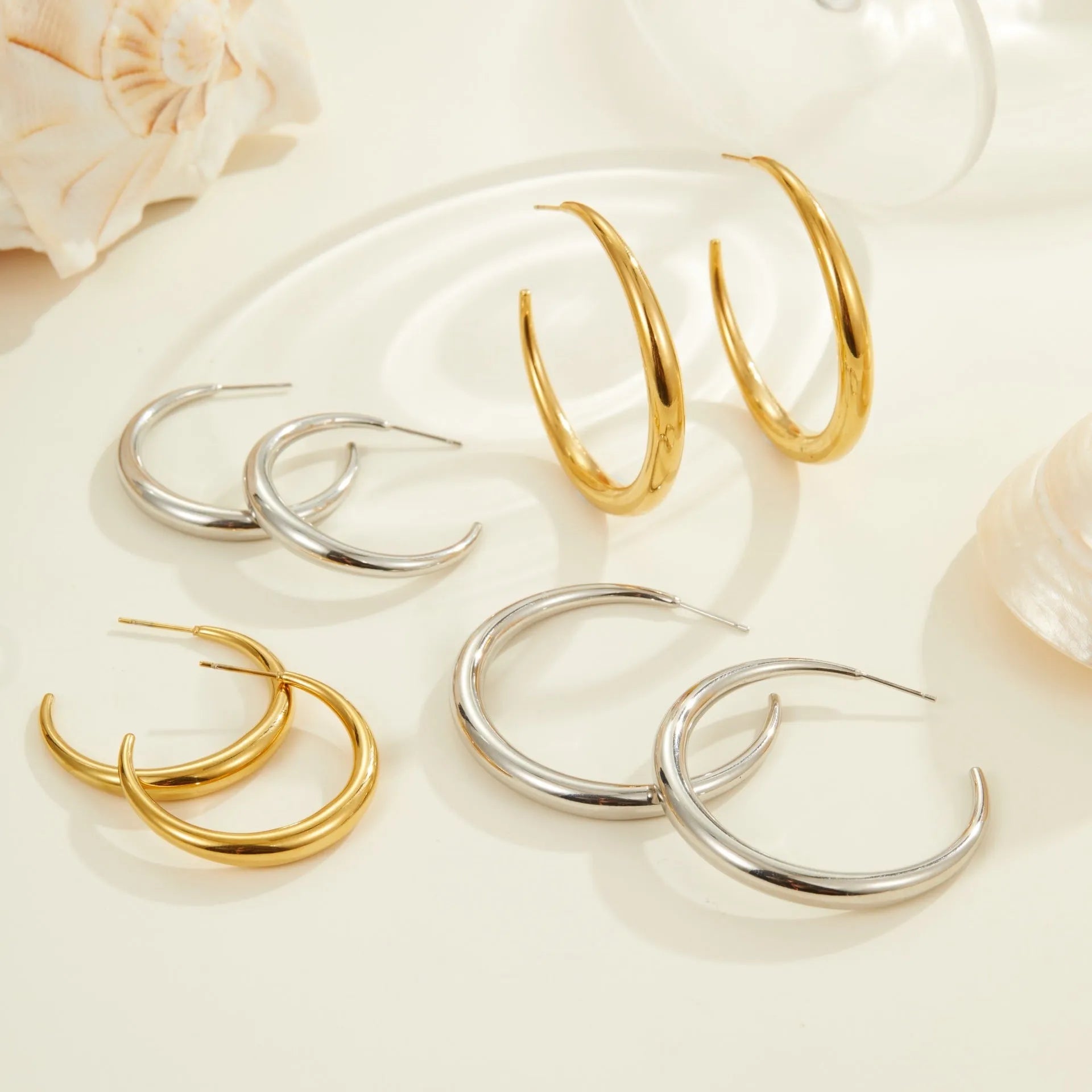 A pair of round titanium steel hoop earrings with an 18K gold plated finish, shown in large and small size options.