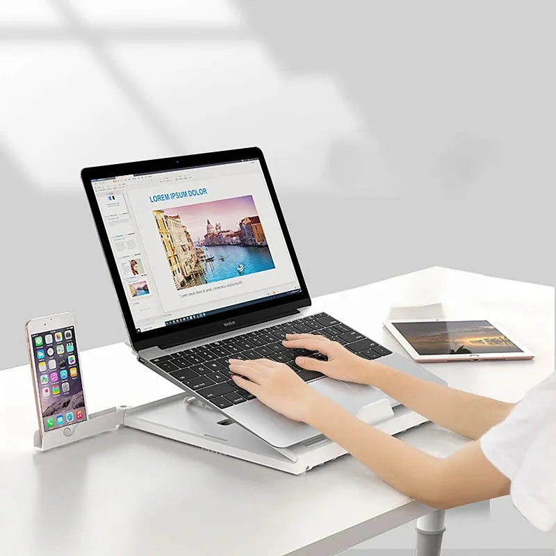 Black folding aluminium laptop stand with 9-level angle adjustment and cooling slot, on a desk with a laptop