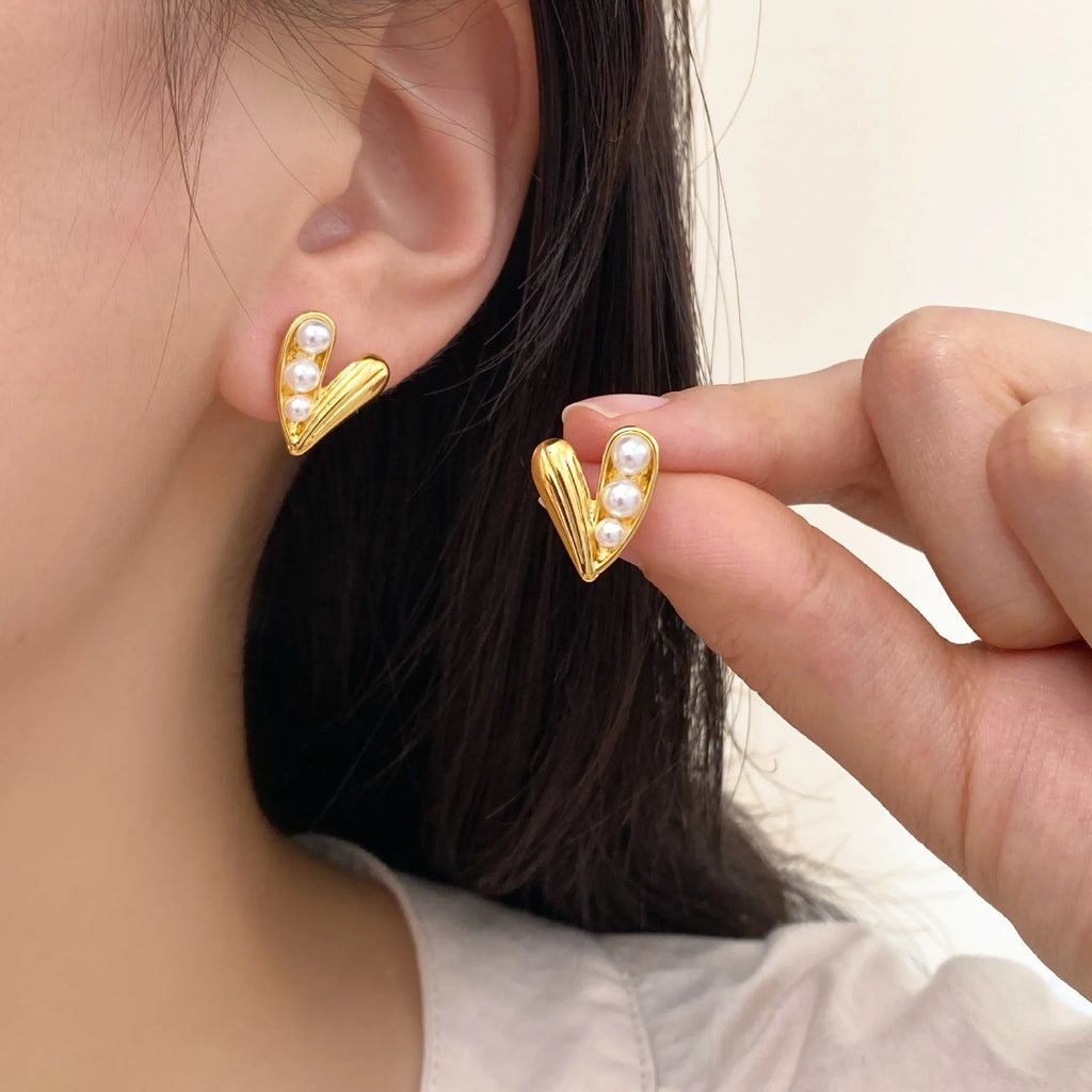 Heart-shaped pearl earrings in copper with electroplated finish, shown as ear clips or ear studs for women.