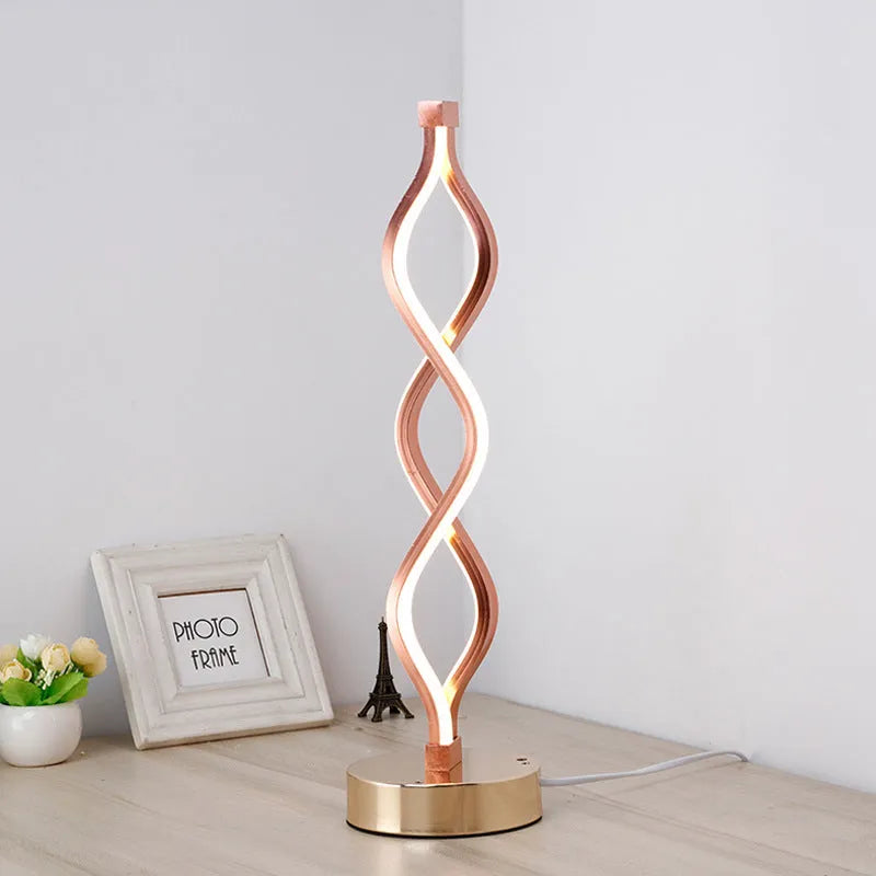 Modern LED desk lamp with aluminium metal body and acrylic mask, gold colour, on a desk