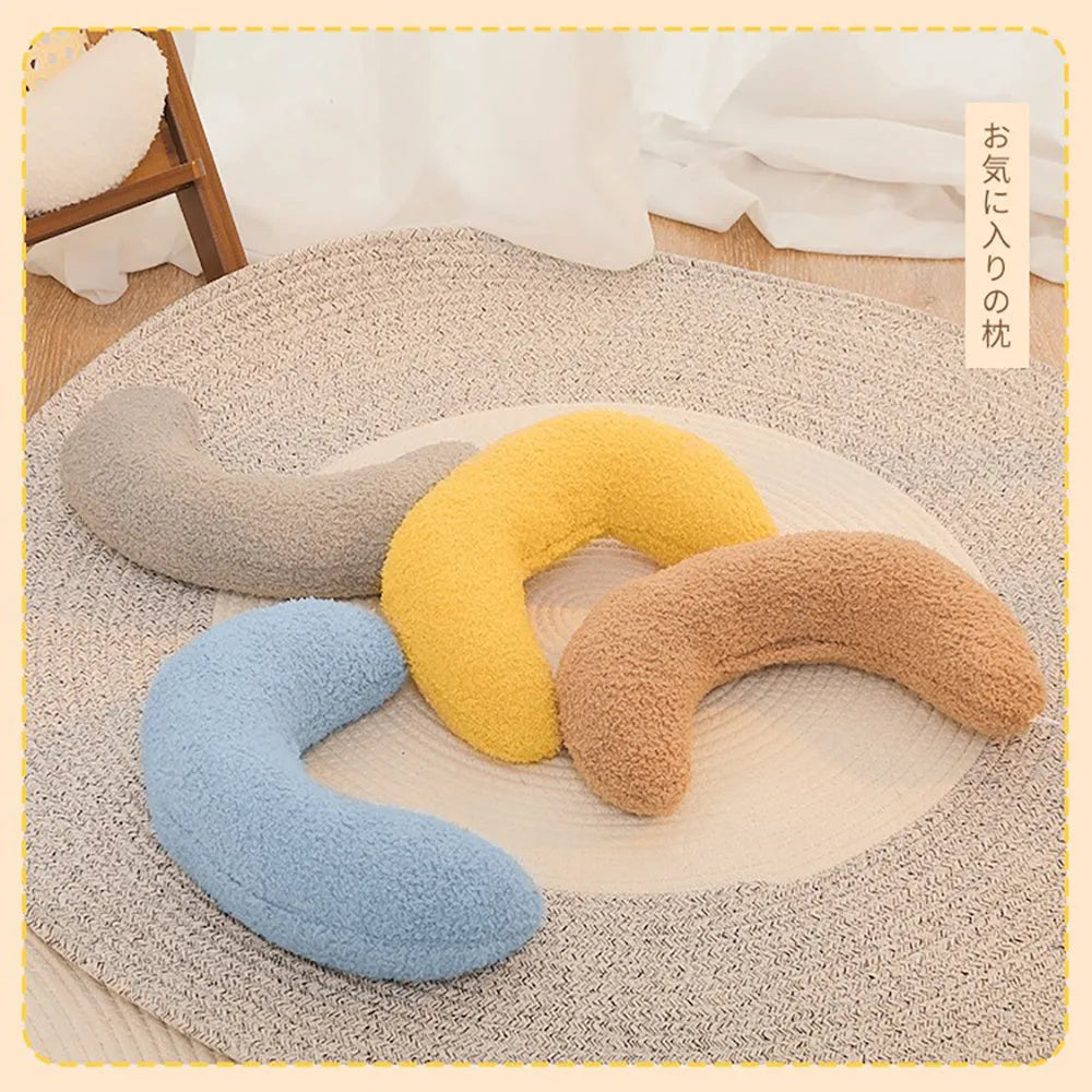 Blue U-shaped cat pillow with a white adjustable padded collar on a grey sofa.