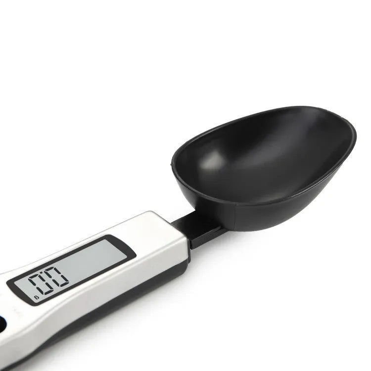 Digital smart measuring spoon with electronic display showing weight, placed on a kitchen worktop.