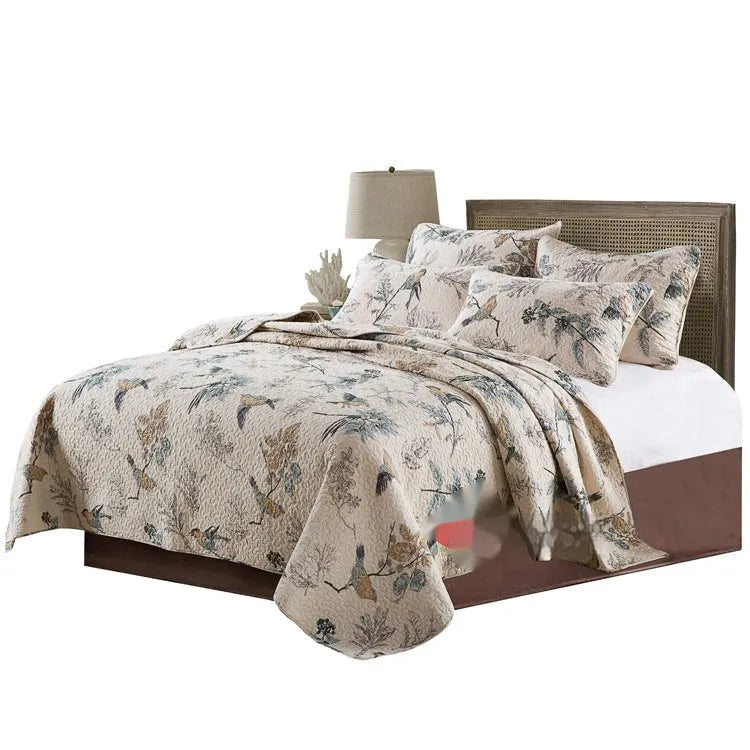 Quilted pure cotton bedspread with decorative stitching and a colourful printed pattern, shown with matching pillowcases on a double bed.