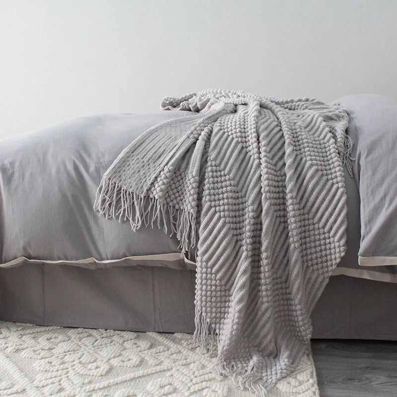 Small light grey polyester fleece blanket folded on a sofa