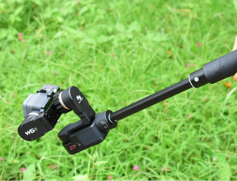 Black retractable aluminium selfie stick with phone clamp attached, shown extended and with a tripod mounted on its base.