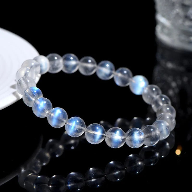 Polished natural cream body blue moonlight crystal bracelet on a wrist, showing simple bead design.
