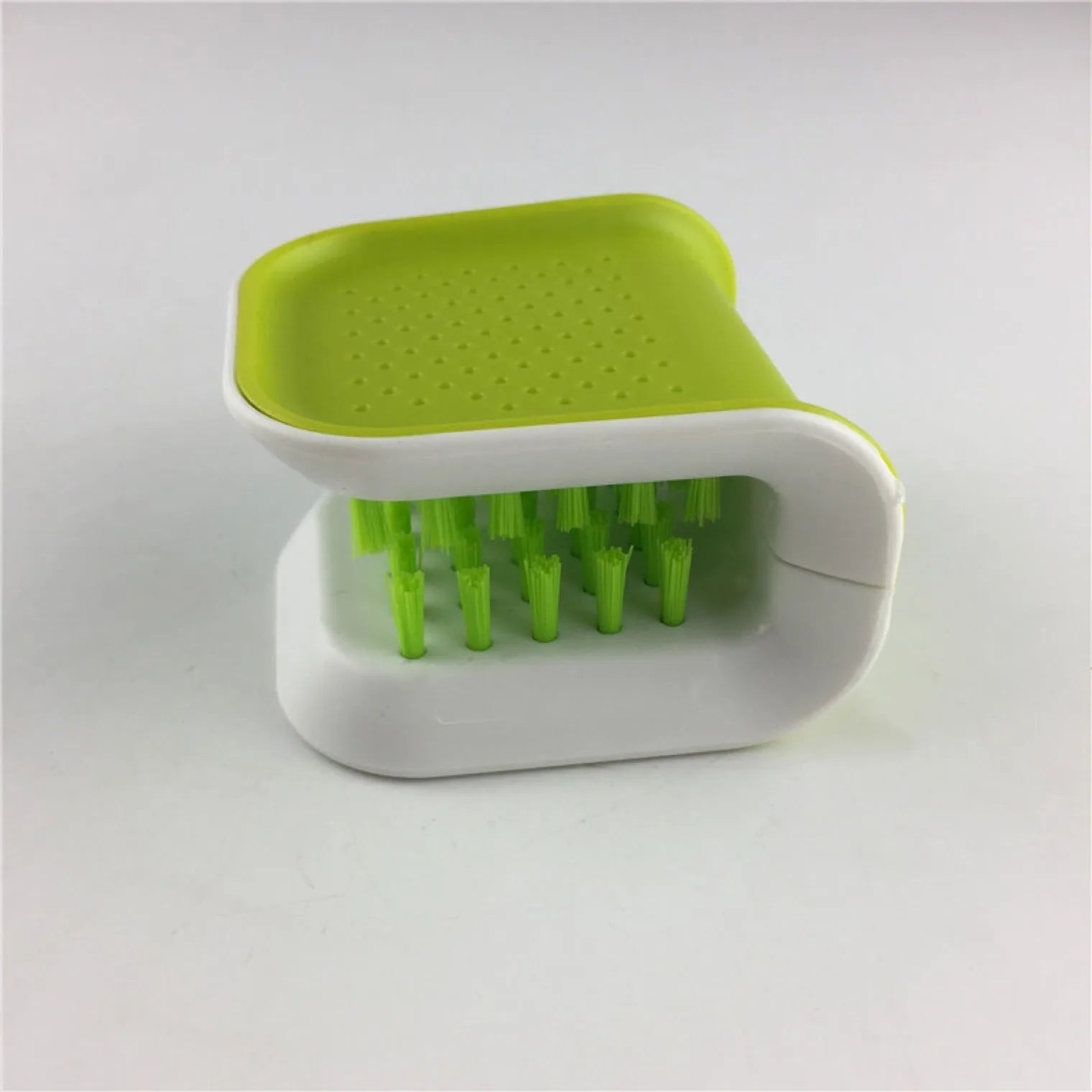 Blue U-shaped plastic brush for cleaning kitchen knives and forks on a draining board.