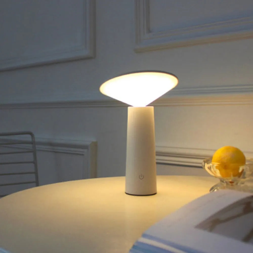 Black USB rechargeable desk lamp with touch sensor base and a tilted lamp head on a wooden desk.