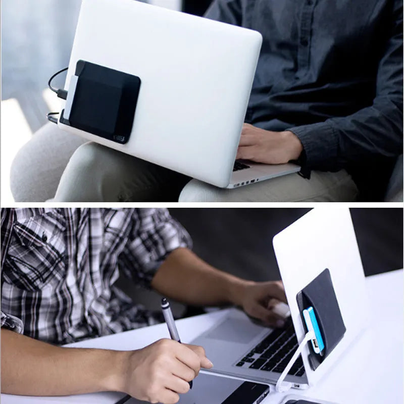 Black adhesive laptop back storage bag attached to a laptop, 15x12 cm, with pen loop and small items inside