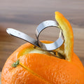 Silver stainless steel kitchen peeler tool with a finger ring for peeling oranges and citrus fruit.
