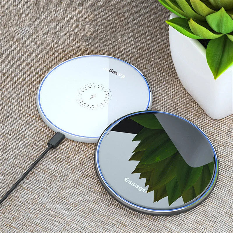 Black aluminium wireless charging pad on a desk with a mobile phone charging on top.