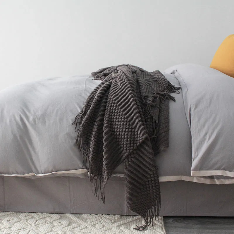 Small light grey polyester fleece blanket folded on a sofa
