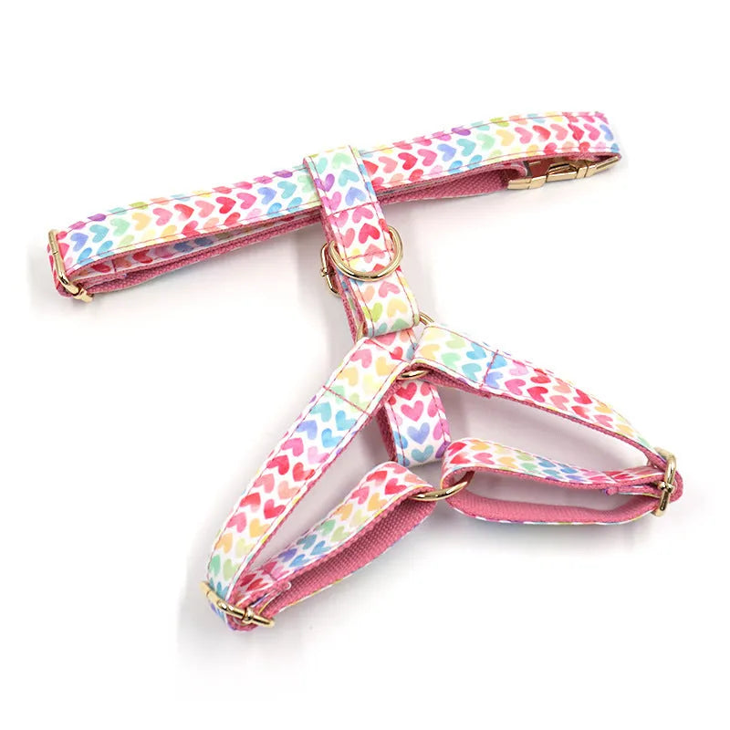 Pink dog harness with gold buckle and heart-shaped stone decoration on white background