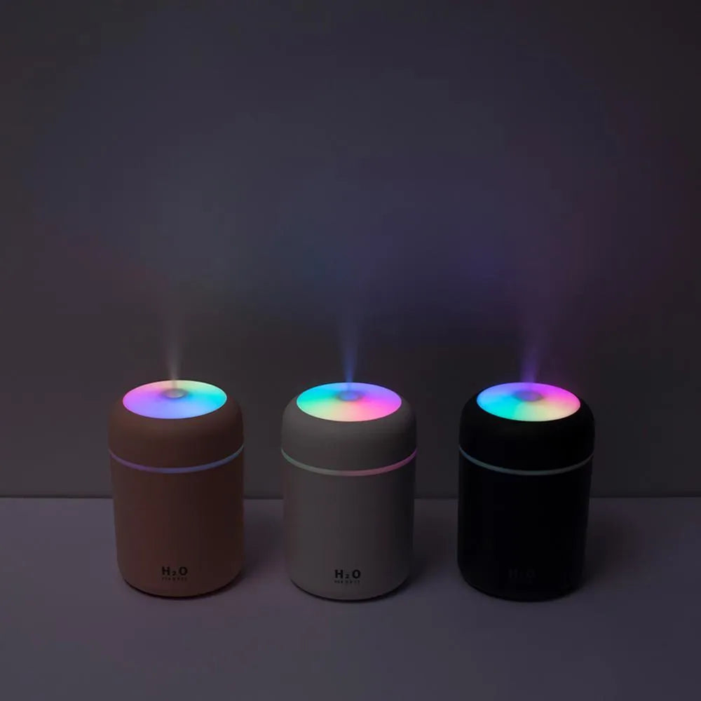 Pink USB desktop humidifier with LED lights and water tank on wooden desk