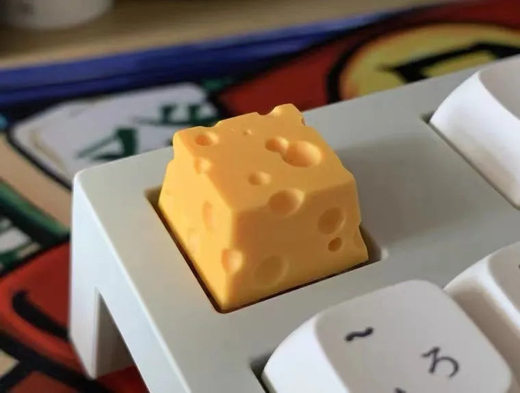 Yellow resin cheese-shaped key cap for mechanical keyboards, shown from a top-down angle.