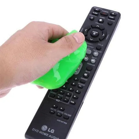 Blue magic cleaning gel putty being pressed onto a laptop keyboard to remove dust.