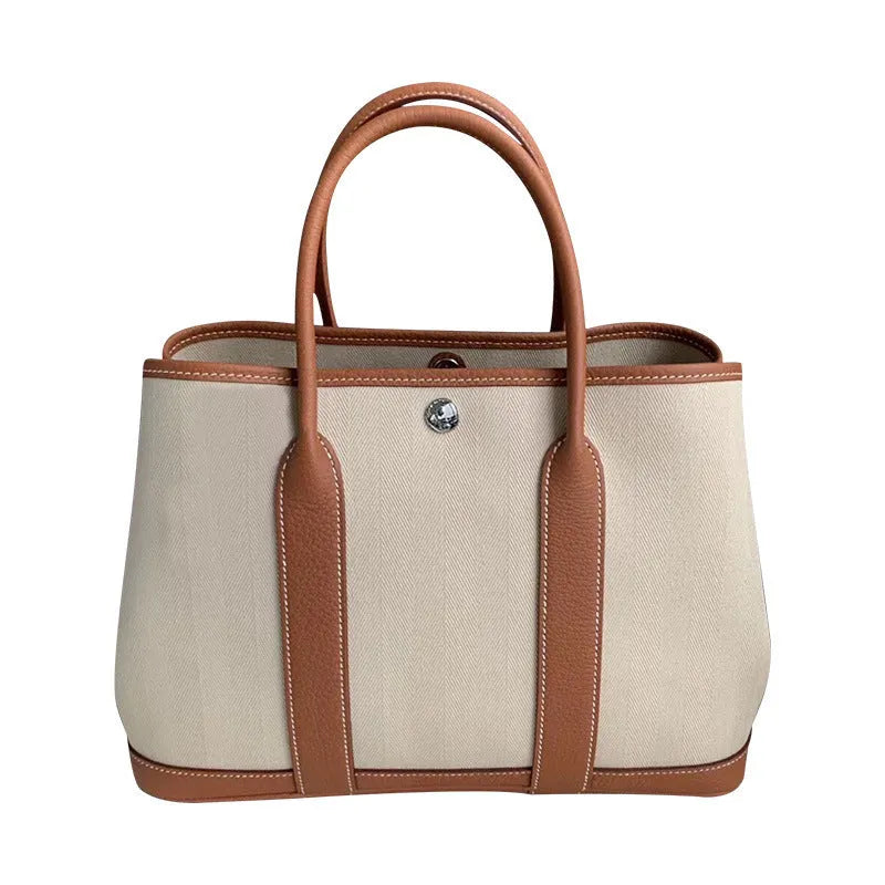 Women's canvas bucket tote bag with leather handles in black, available with crossbody strap and open top pocket