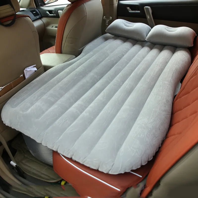 Black car inflatable bed with two pillows, shown inflated in a vehicle's rear compartment.