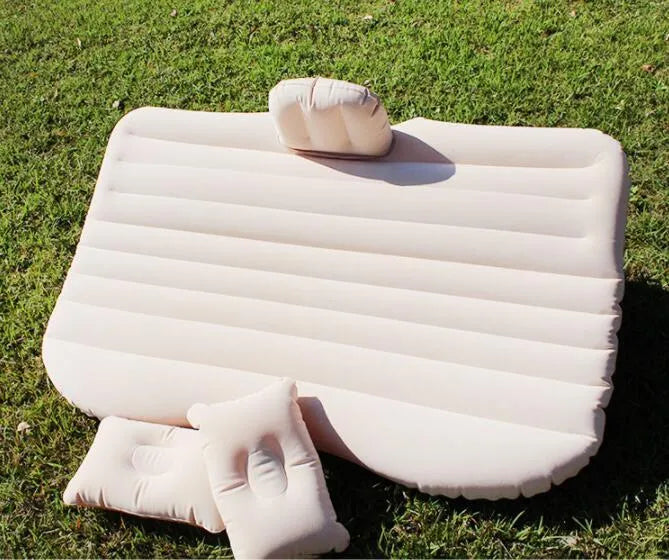 Black car inflatable bed with two pillows, shown inflated in a vehicle's rear compartment.