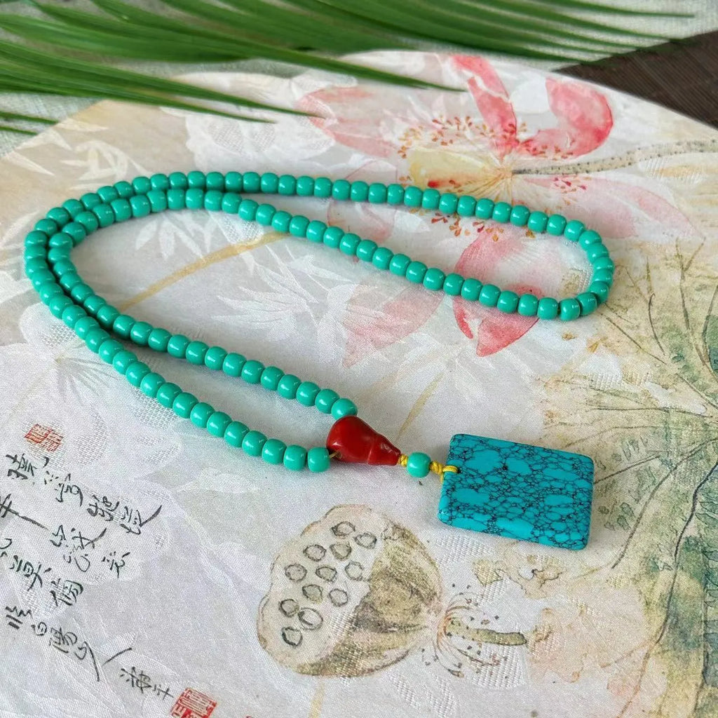 Hand-woven turquoise mesh flower lucky pendant on an adjustable ball bead necklace.