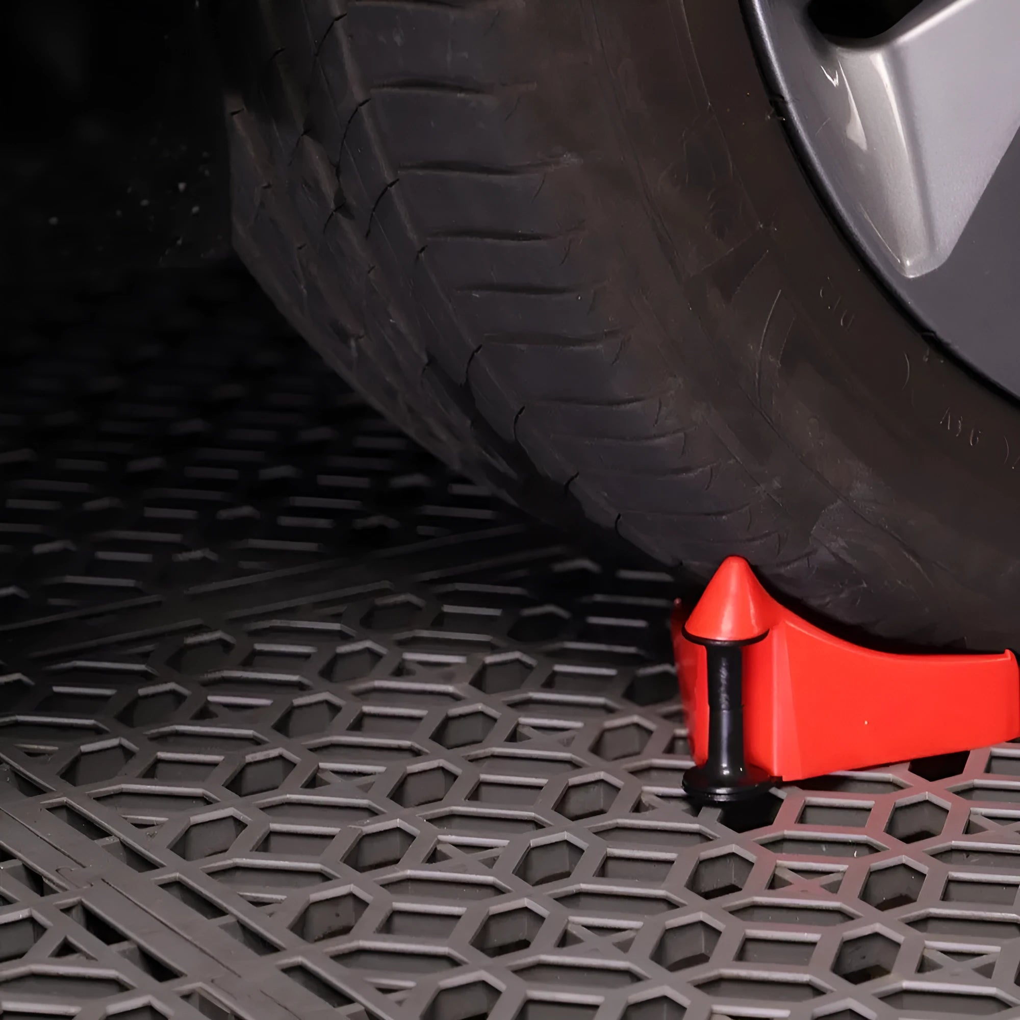 Four red plastic triangular car parking blocks arranged on a grey surface