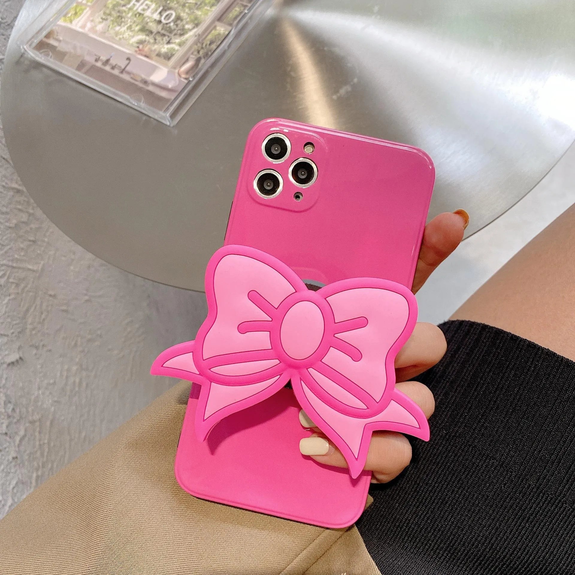 Rose red iPhone case with a pink bow design and a fold-out kickstand on the back.
