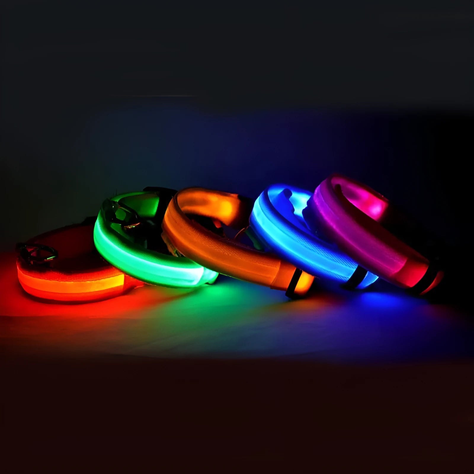 Nylon LED pet collar with adjustable buckle in blue, glowing with fibre optic lights in flash mode on a dark surface