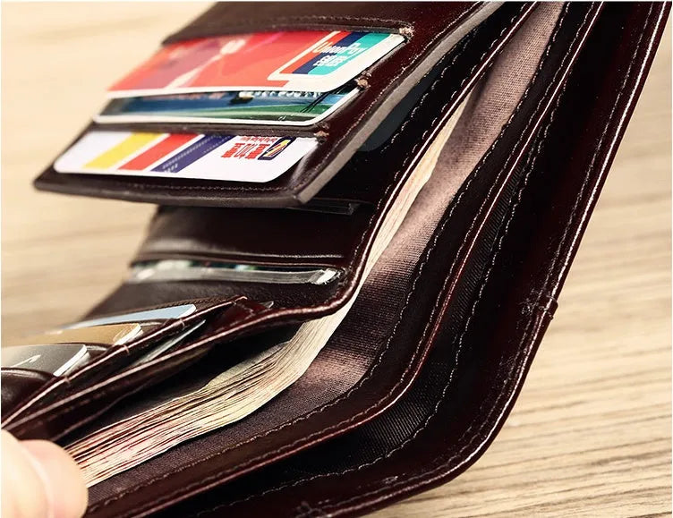 Men's black leather bifold wallet open, showing eight card slots, bill compartment, and a zip coin pocket