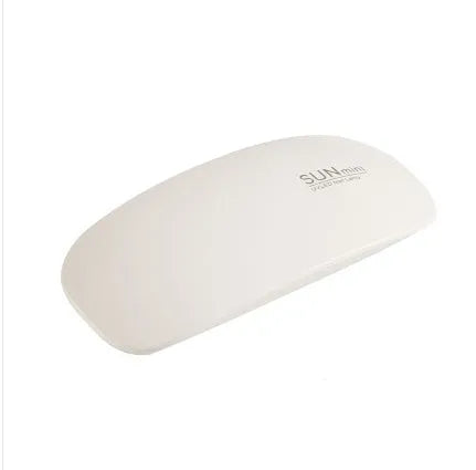 Portable nail dryer in white colour with phototherapy lamp and sealing function on a table