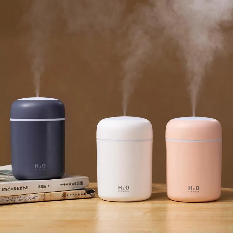 Pink USB desktop humidifier with LED lights and water tank on wooden desk