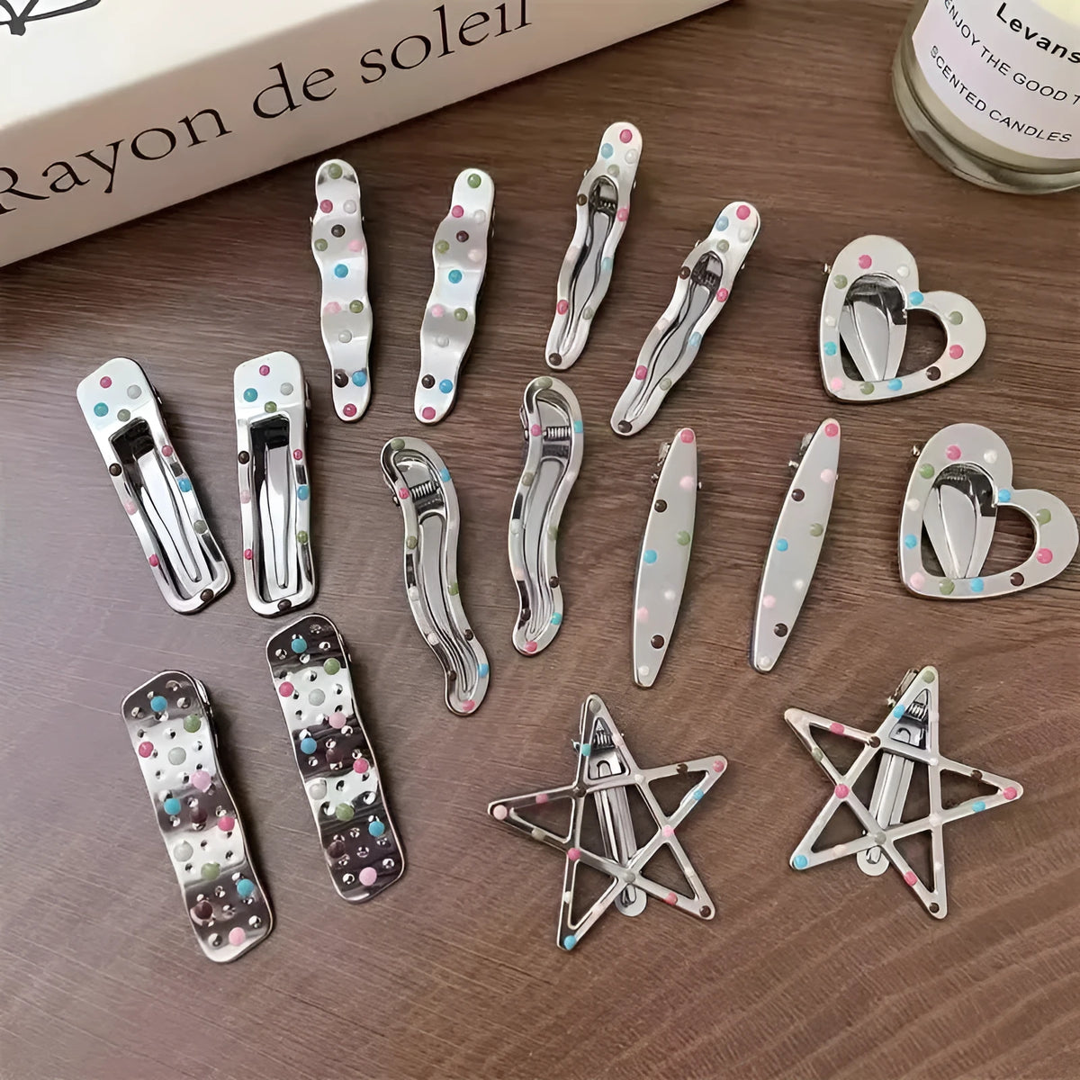 Two electroplated metal duckbill hairpins with hollow heart, star, and wave cut-out designs in silver tone