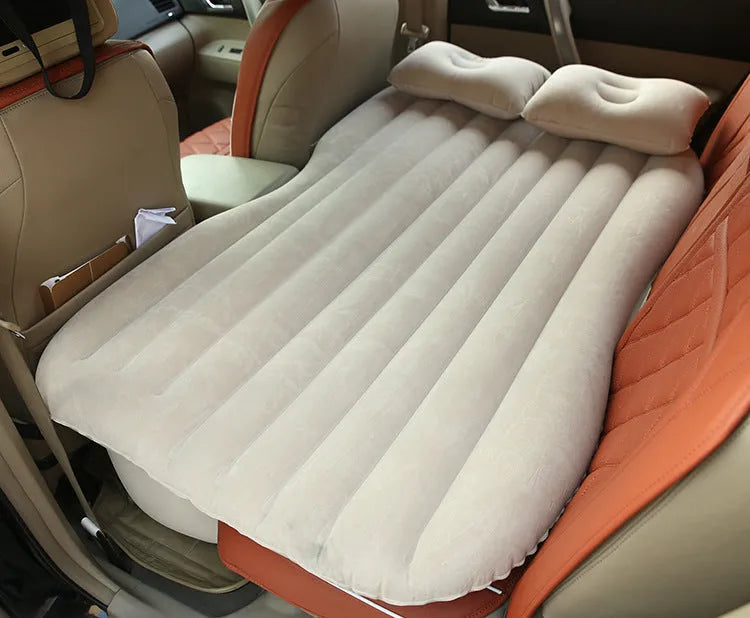 Black car inflatable bed with two pillows, shown inflated in a vehicle's rear compartment.