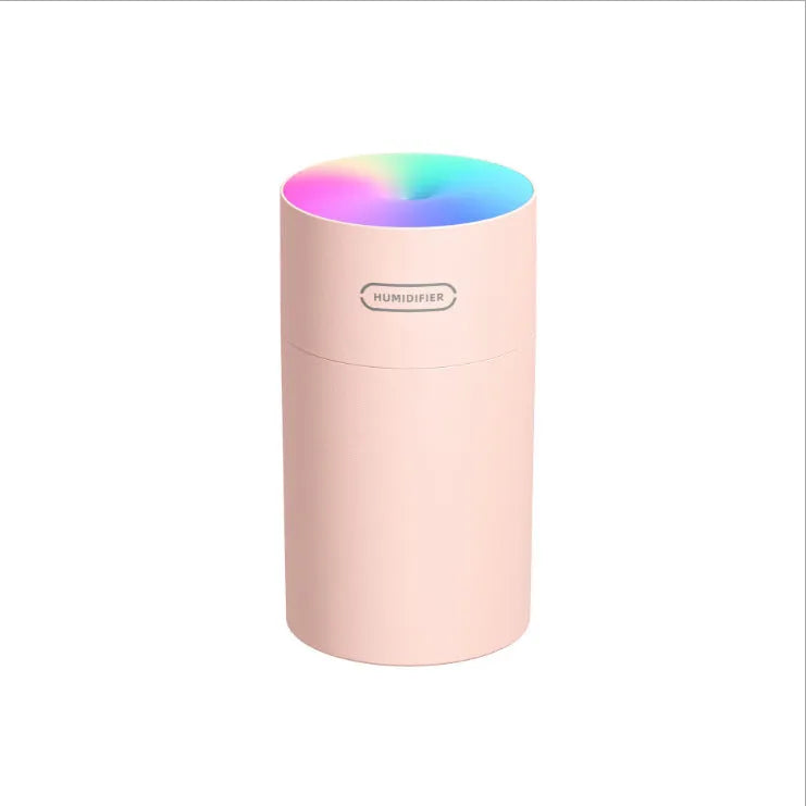 Pink USB desktop humidifier with LED lights and water tank on wooden desk