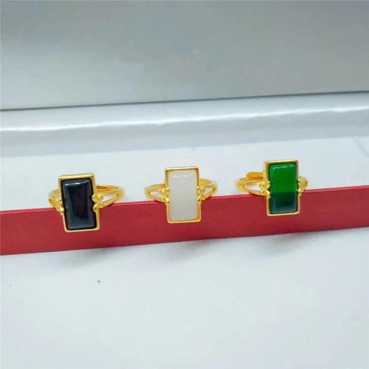 Close-up of an adjustable brass gold-plated ring with an electroplated finish and a green artificial gemstone inlay.