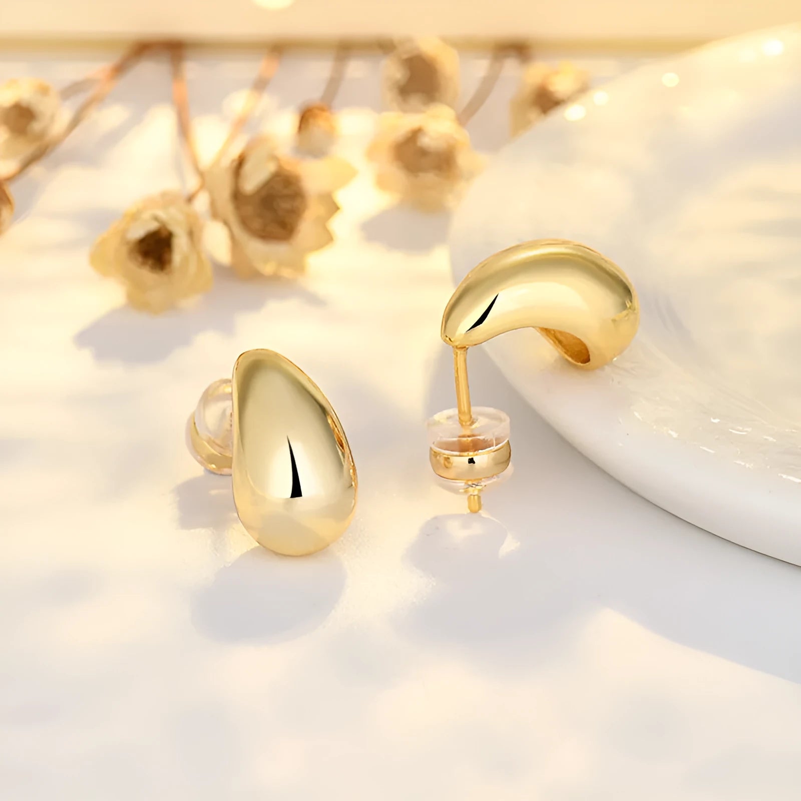 Minimalistic water drops earrings in gold plated copper, drop shape stud style on white background