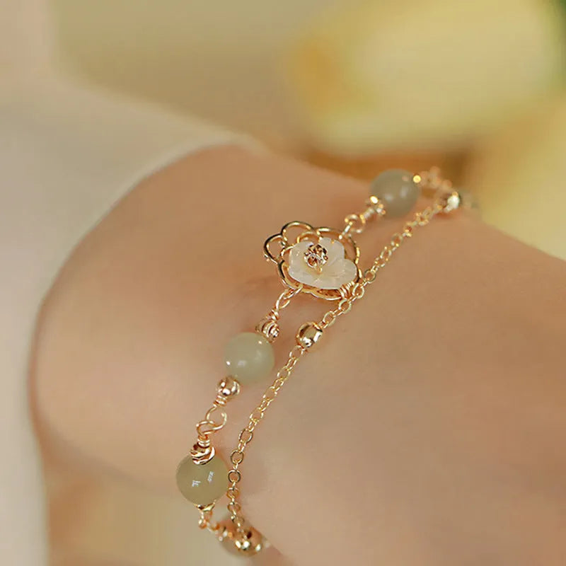 Yellow gold electroplated butterfly bracelet with shell flower design and Hetian jade accents on geometric copper jewellery