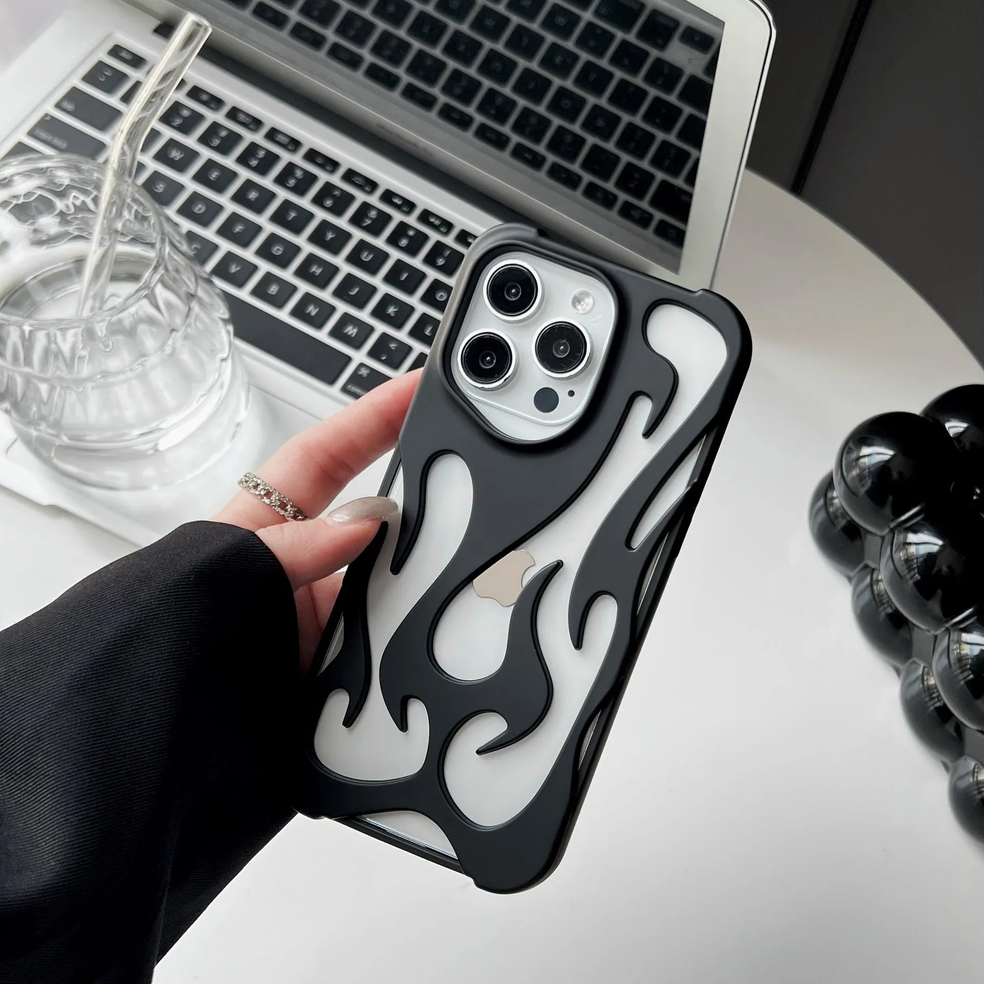 Electroplated hollow flame pattern phone case for iPhone on a table, showing silver metallic finish and cut-out design.