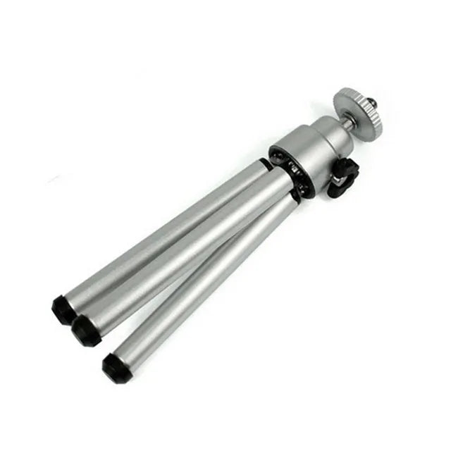Mini aluminium tripod extended with ball head, shown alongside a U-shaped smartphone clip on a table.
