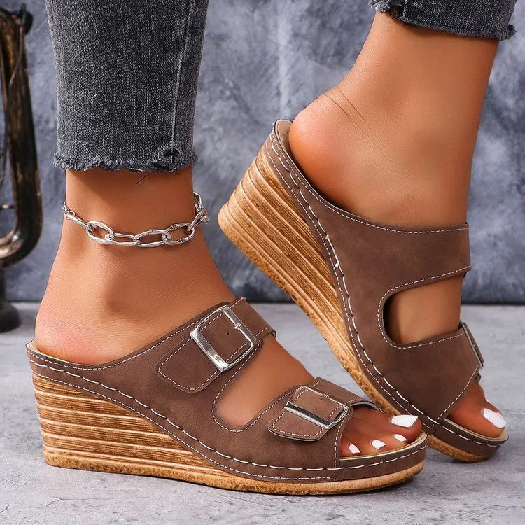 Creamy-white women's wedge slippers with a buckle strap on a black sole.