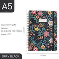 A5 spiral notebook with colourful floral cover design, lying open on a flat surface.