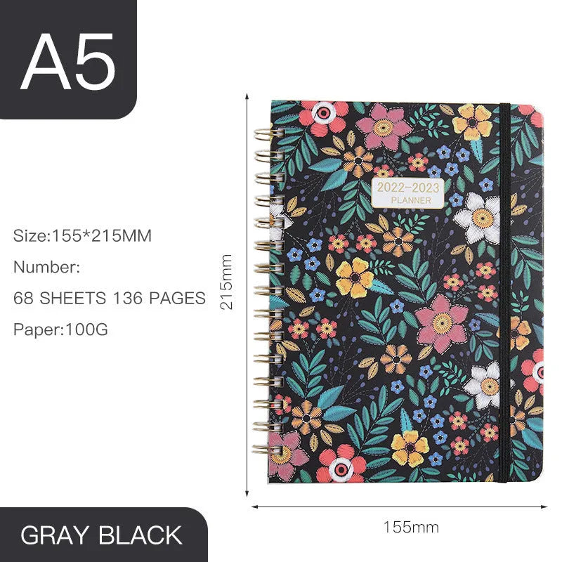 A5 spiral notebook with colourful floral cover design, lying open on a flat surface.