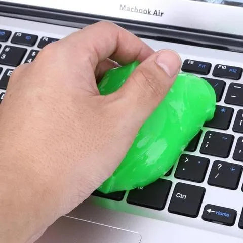 Blue magic cleaning gel putty being pressed onto a laptop keyboard to remove dust.