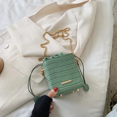 Small black one-shoulder bucket bag with a silver detachable chain strap and magnetic flap closure.